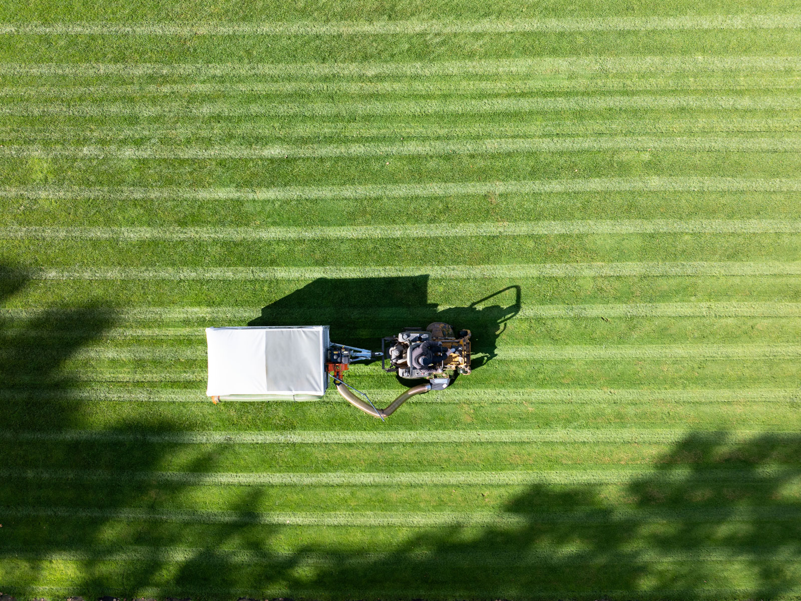Aerial view of a Foresteel FT-COMBIvac collecting grass clippings behind a mower on a sports field.